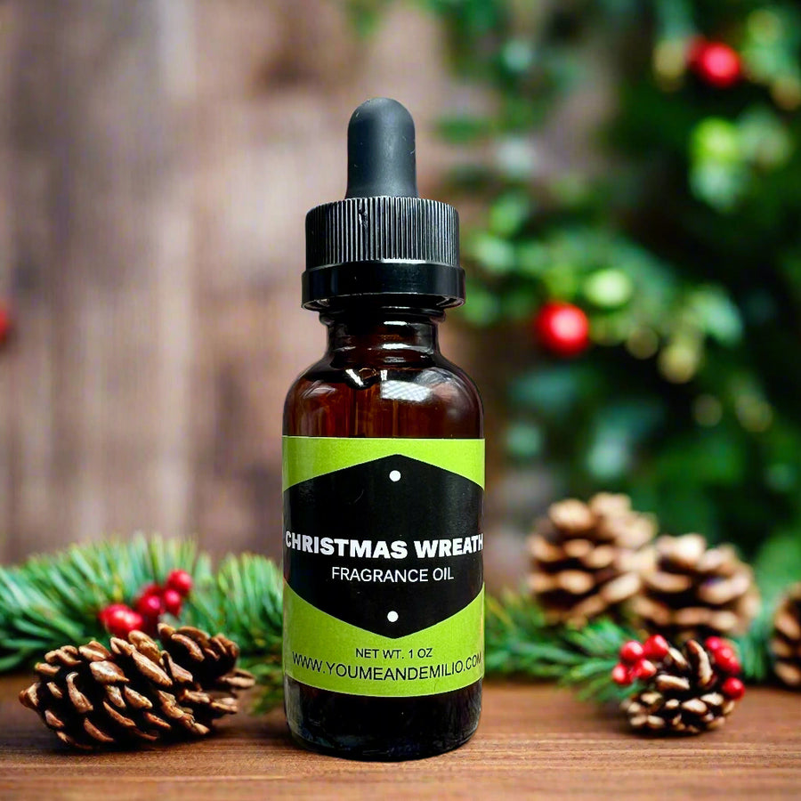 Christmas Wreath Fragrance Oil in an elegant glass bottle, surrounded by pinecones and holly for a holiday-themed aesthetic.