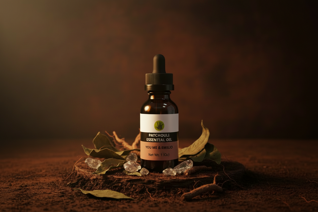 YOU ME & EMILIO Patchouli Essential Oil amber dropper bottle on dark wood with dried patchouli leaves, moody earthy aesthetic