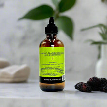 Bottle of Almond Blackberry Sage Lotion with a backdrop of fresh blackberries, almonds, and sage leaves.