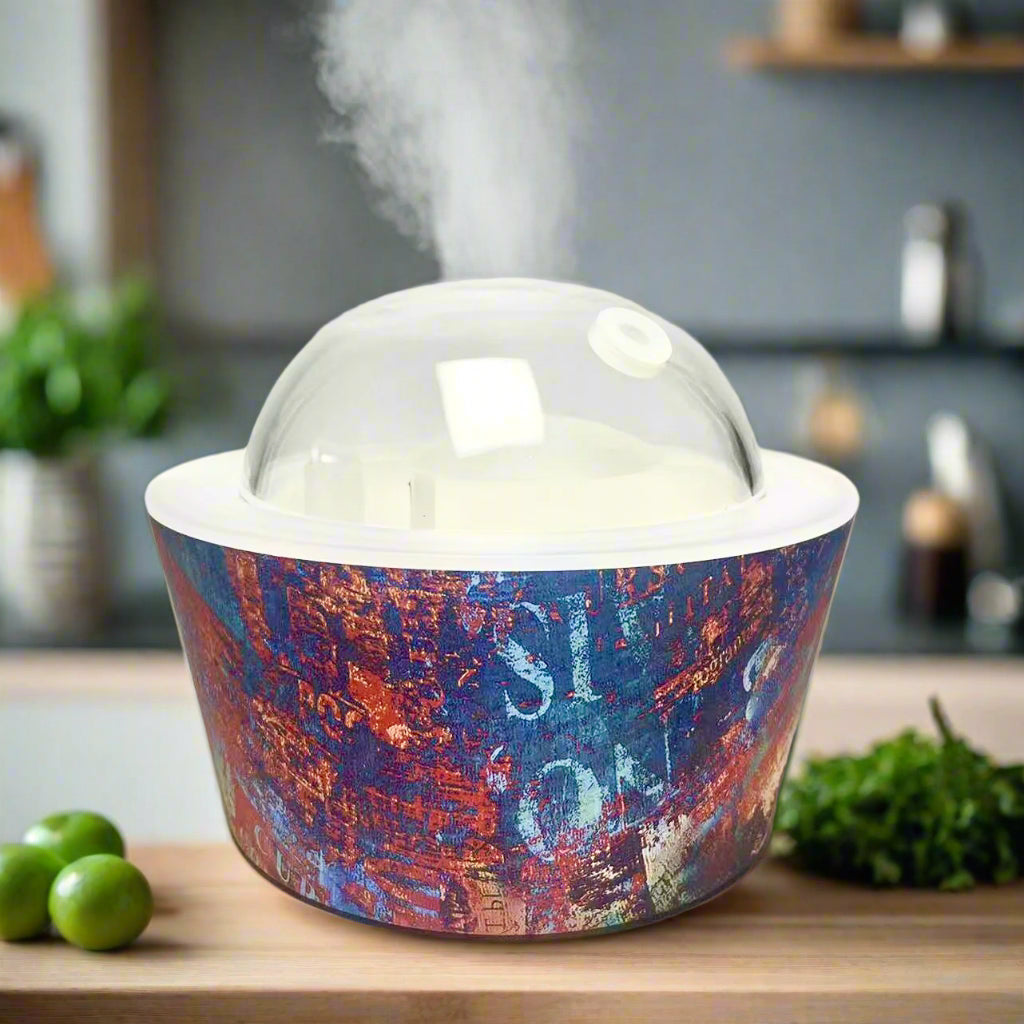 Artistic Essence Oil Diffuser featuring vibrant abstract blue, red, and gold design with a clear dome top by YOU ME & EMILIO.