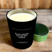 A Tom Ford Inspired Black Orchid Deluxe Soy Candle flickering warmly on a stylish tabletop, exuding luxury and elegance.
