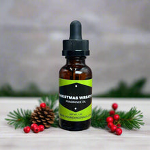 Christmas Wreath Fragrance Oil displayed on a rustic wooden table, paired with twinkling fairy lights and evergreen sprigs for a festive touch.