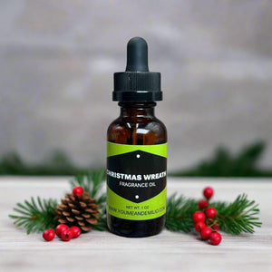 Christmas Wreath Fragrance Oil displayed on a rustic wooden table, paired with twinkling fairy lights and evergreen sprigs for a festive touch.