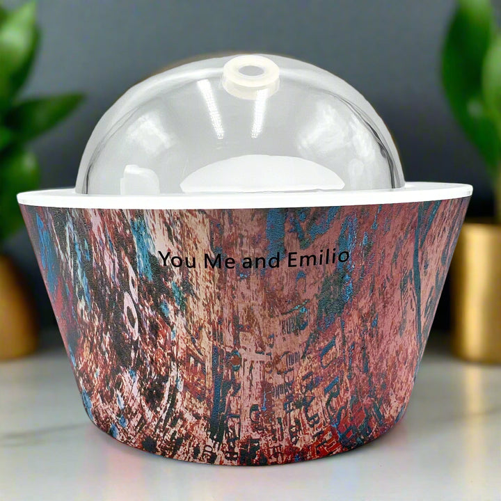 Artistic Essence Oil Diffuser, a masterful creation from Emilio Horton, founder of YOU ME &amp; EMILIO. Featuring a vibrant, textured abstract design of deep blues, fiery reds, and shimmering gold, this diffuser transforms any space into a sanctuary of creativity, relaxation, and sensory delight.

More than just an aromatherapy tool, the Artistic Essence brings an immersive experience with the gentle sound of running water and soft mist creation, inspired by the tranquility of natural streams.