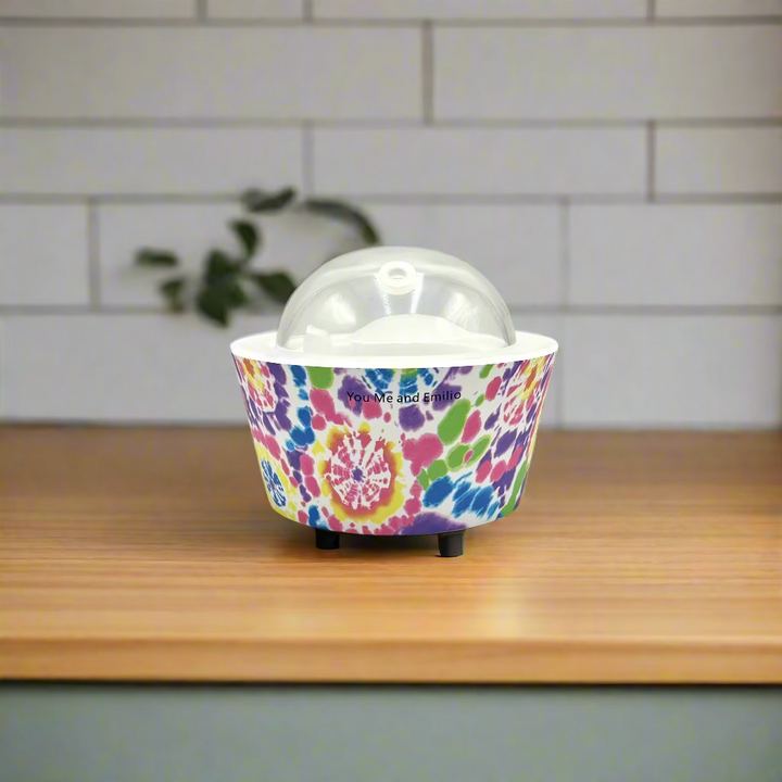 Colorful tie-dye patterned container with a clear dome lid on a white background