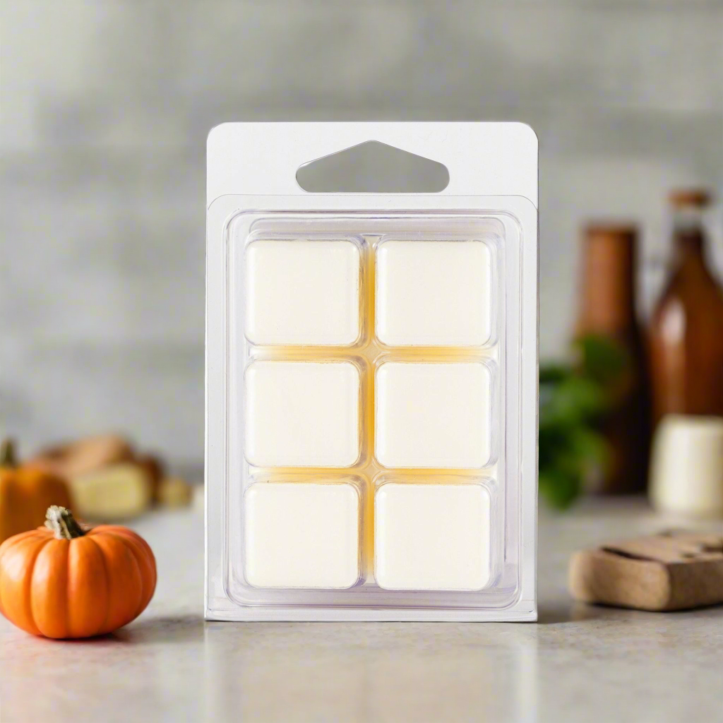 Pack of six wax melts in a clear plastic packaging on a neutral background with decorative items.