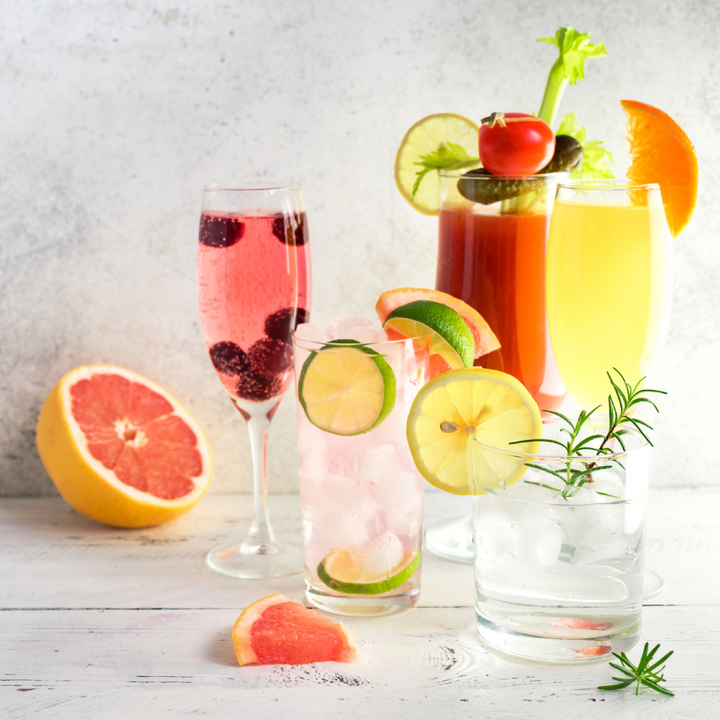 Assorted cocktails with fruits and garnishes on a wooden surface