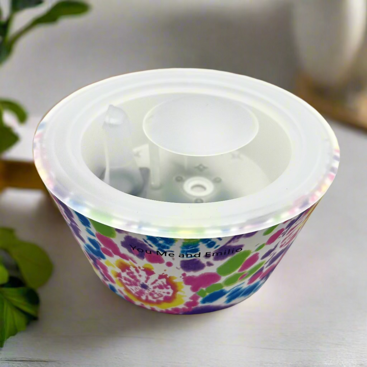Colorful tie-dye patterned container with a clear lid on a white background