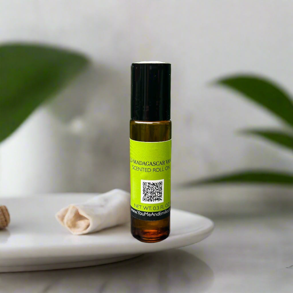 Amber bottle of Wild Madagascar Vanilla Roll-On Perfume Oil by You Me & Emilio, featuring notes of African pear, wild jasmine, Madagascar vanilla, and sandalwood.