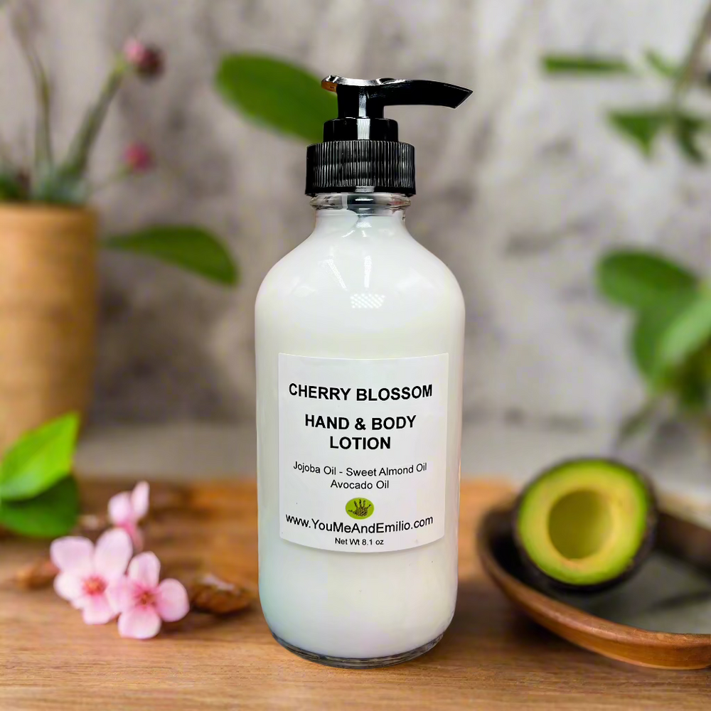 Bottle of Cherry Blossom Hand & Body Lotion surrounded by vibrant cherry blossoms and wildflowers, emphasizing its delicate fragrance.