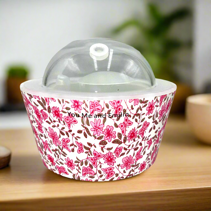 Decorative container with floral pattern and clear lid on a white background