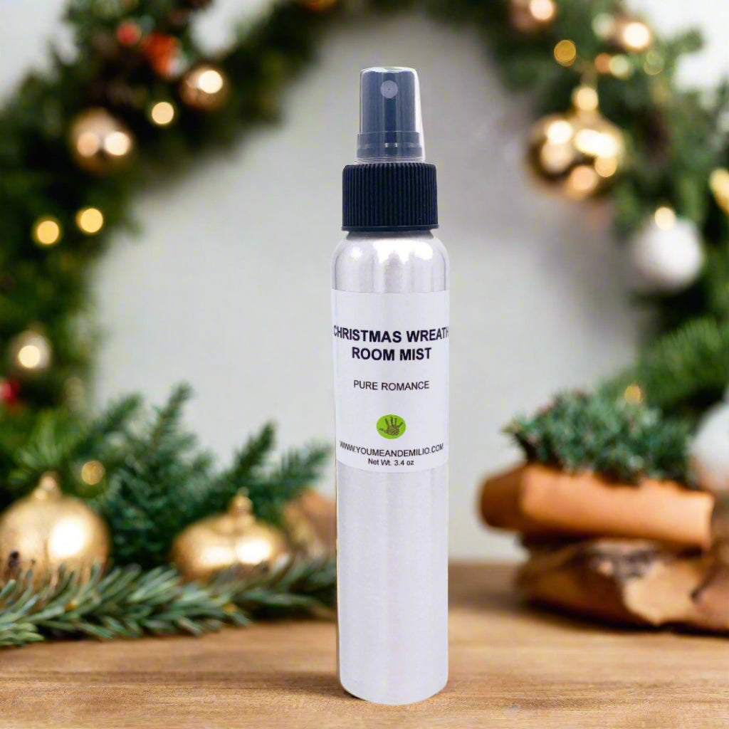 Polished cylindrical aluminum bottle of Christmas Wreath Room Mist displayed on a festive tray, with snow-dusted pine needles, cinnamon sticks, and warm lights.