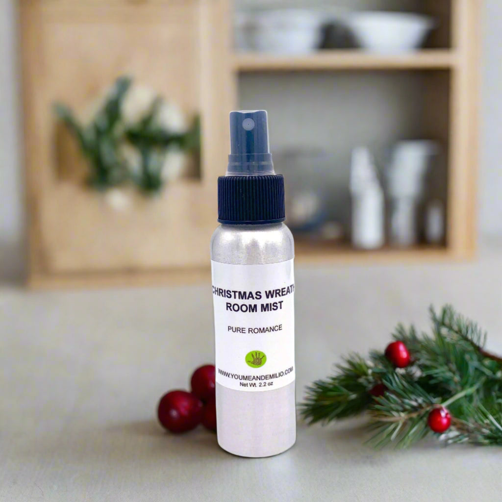 Christmas Wreath Room Mist in a stylish aluminum container, accompanied by sprigs of evergreen, holly berries, and glowing holiday accents in the background.